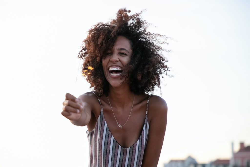 happy black woman with afro hairstyle and outstretched arm outdoors